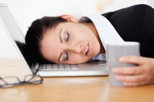 Businesswoman sleeping with cup of coffee in her hand